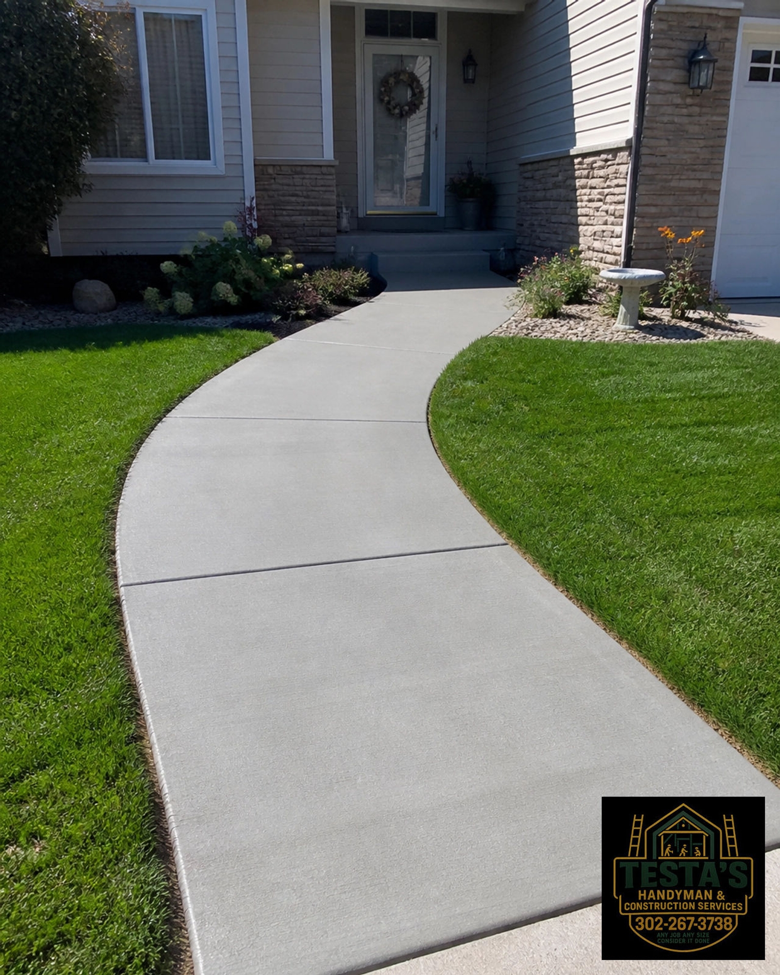 A smooth concrete walkway curves through a green lawn, leading to a house’s front entrance. HASTA'S sign shown.