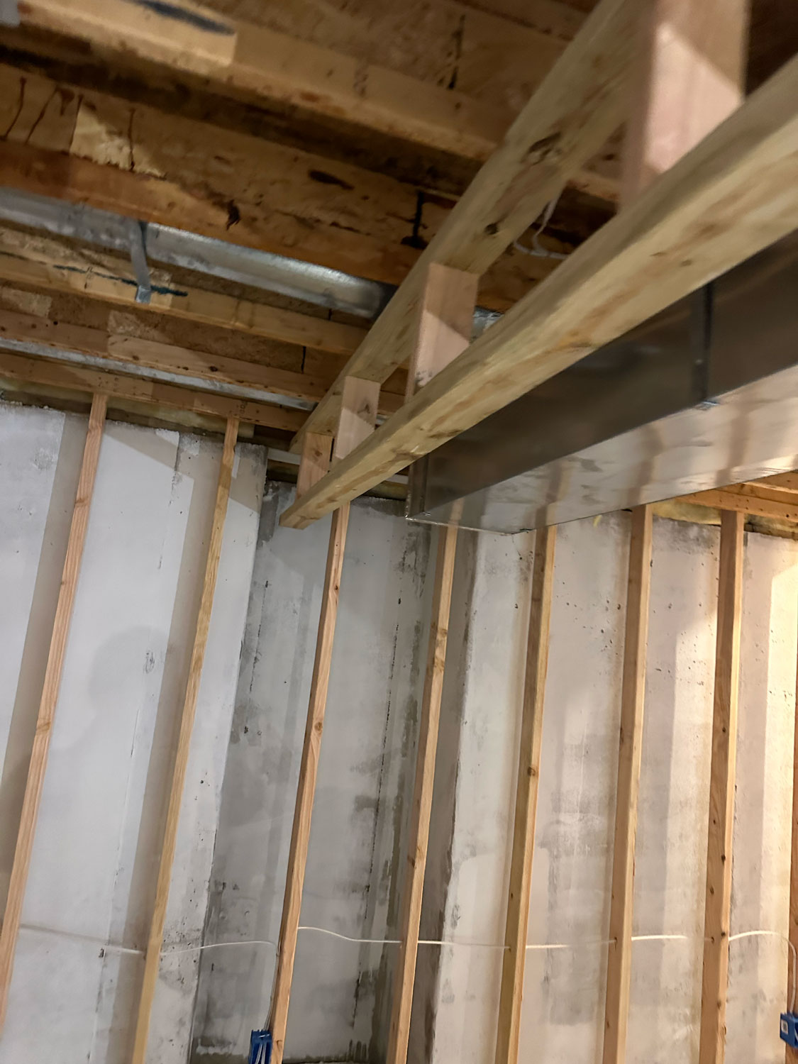 Unfinished basement with exposed wooden framing, ceiling beams, and visible metal ductwork.