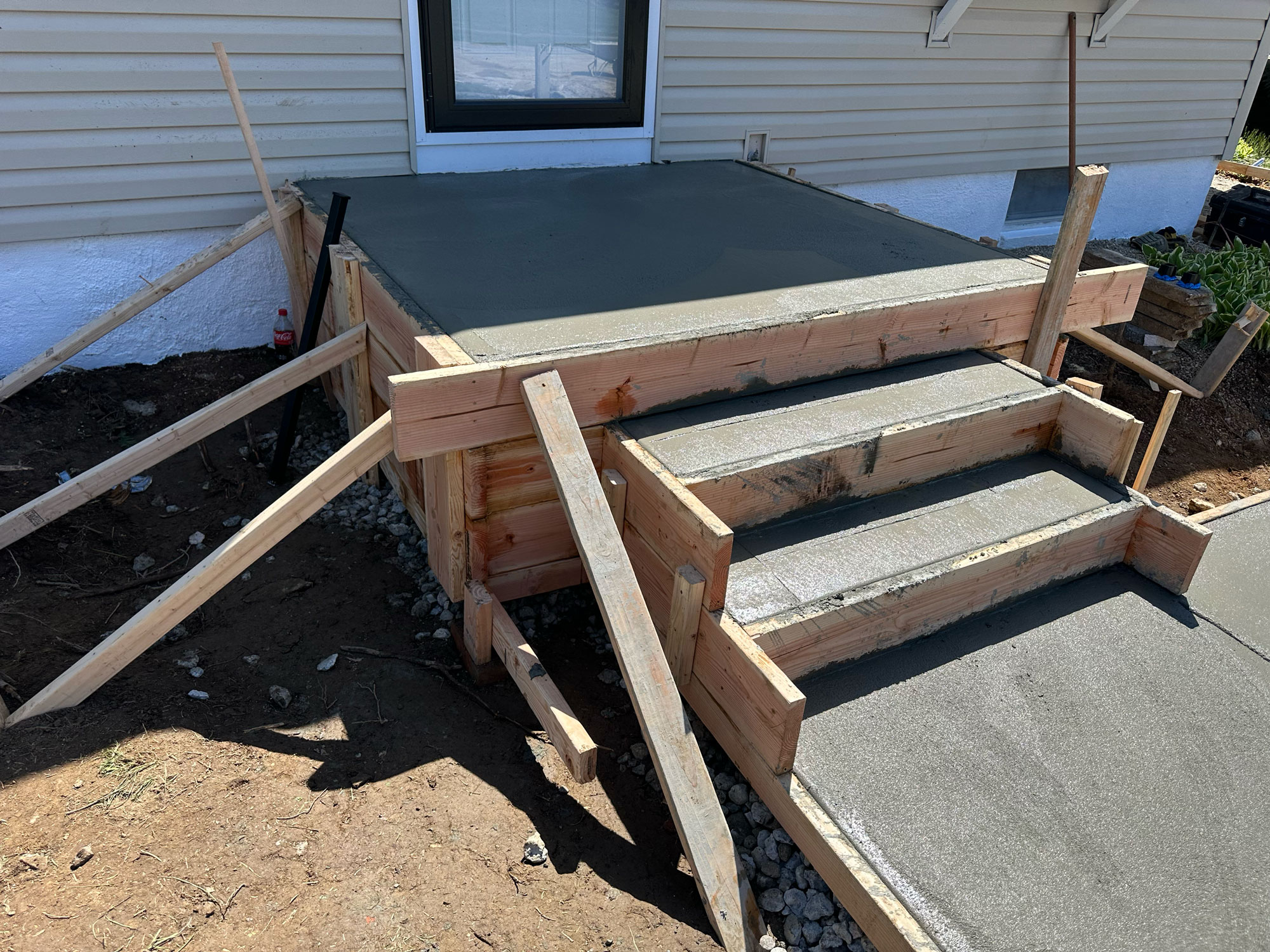Freshly poured concrete steps and porch with wooden forms and support beams still in place.